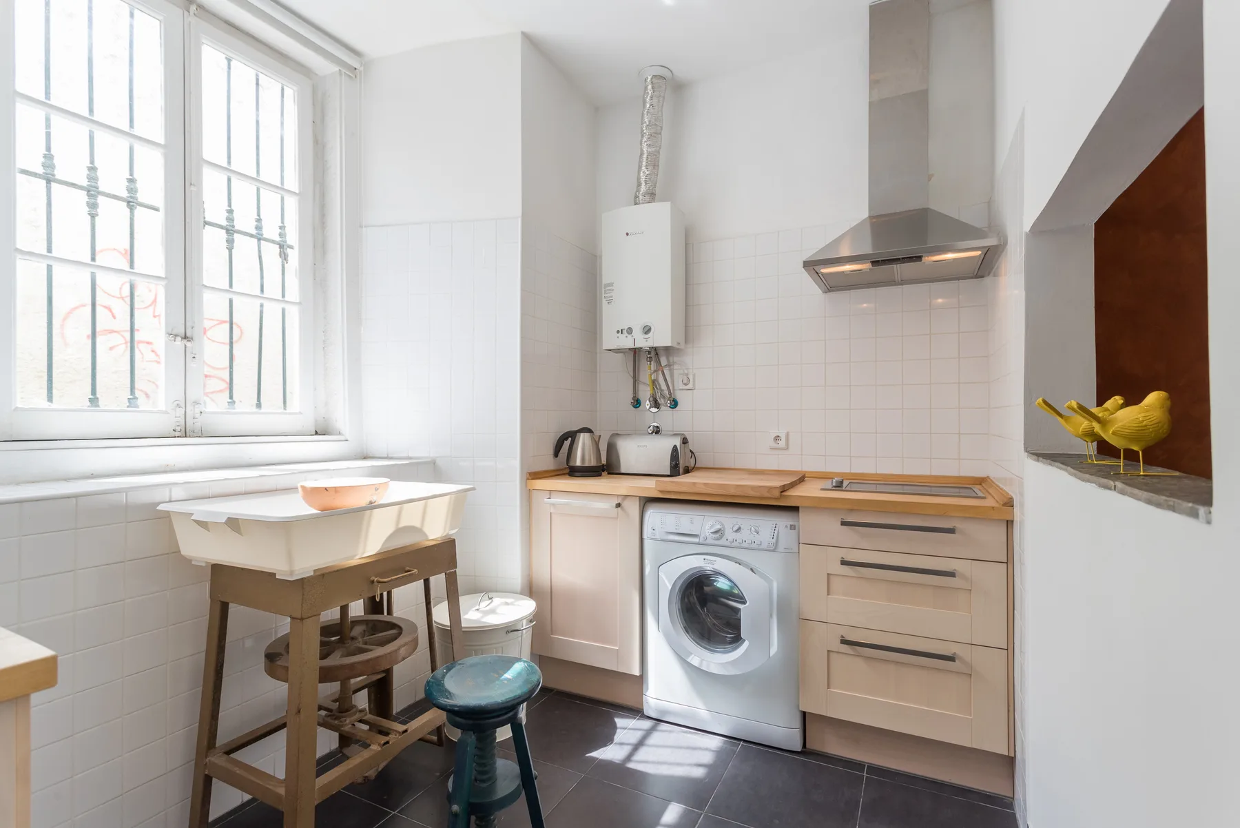 Una cocina luminosa con fregadero, lavadora y encimera junto a una ventana grande.