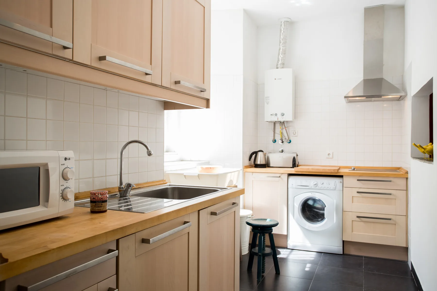 Una cocina luminosa con armarios de madera, un fregadero y una lavadora.