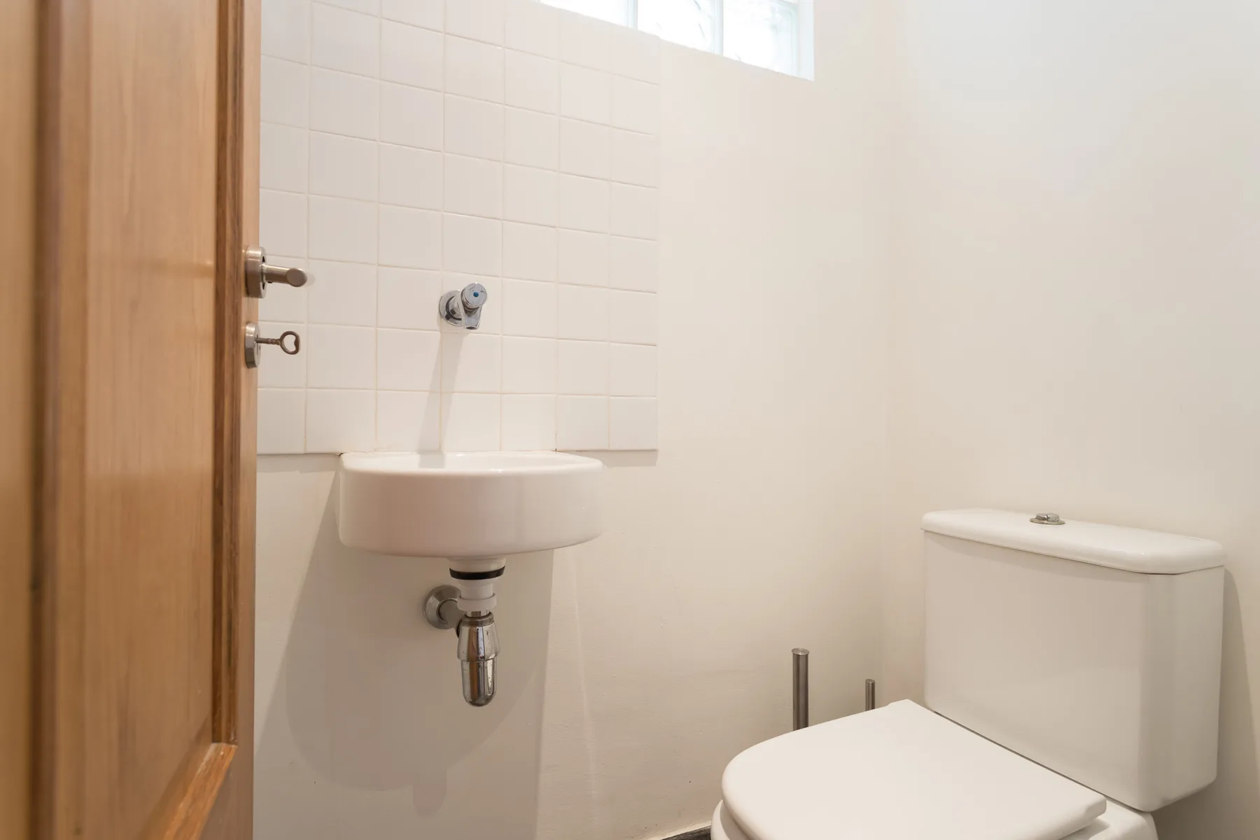 Un baño luminoso con lavabo e inodoro junto a una pared de azulejos.