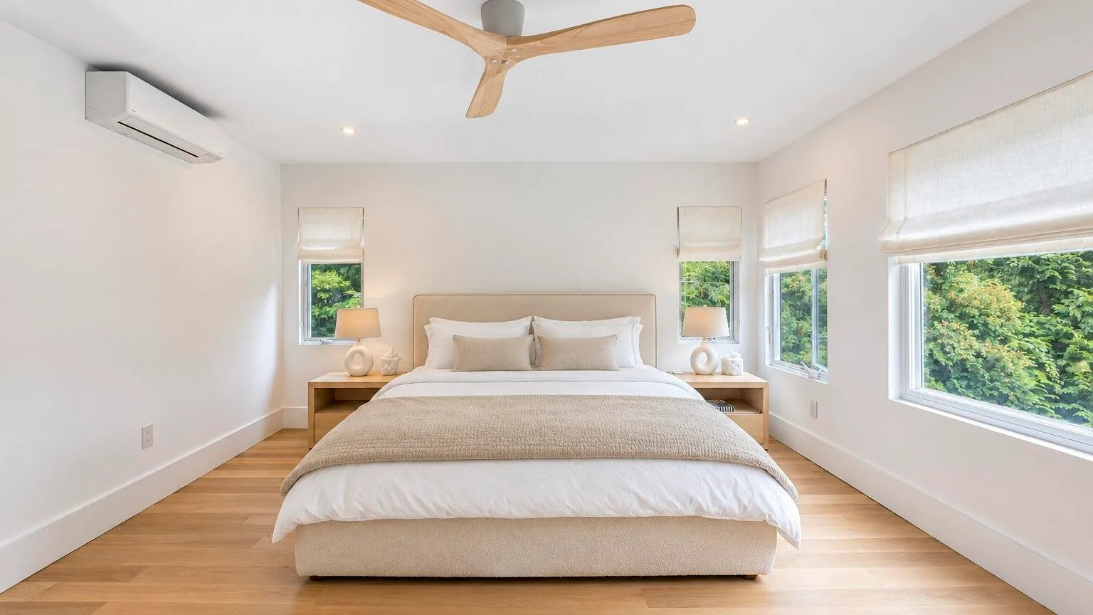 A bright bedroom with a bed centered between windows.