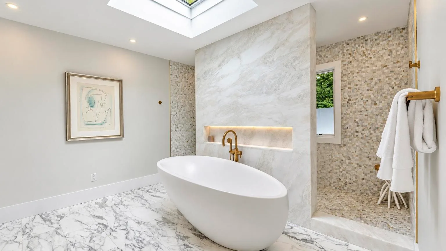 A bright bathroom with a freestanding bathtub beneath a skylight.