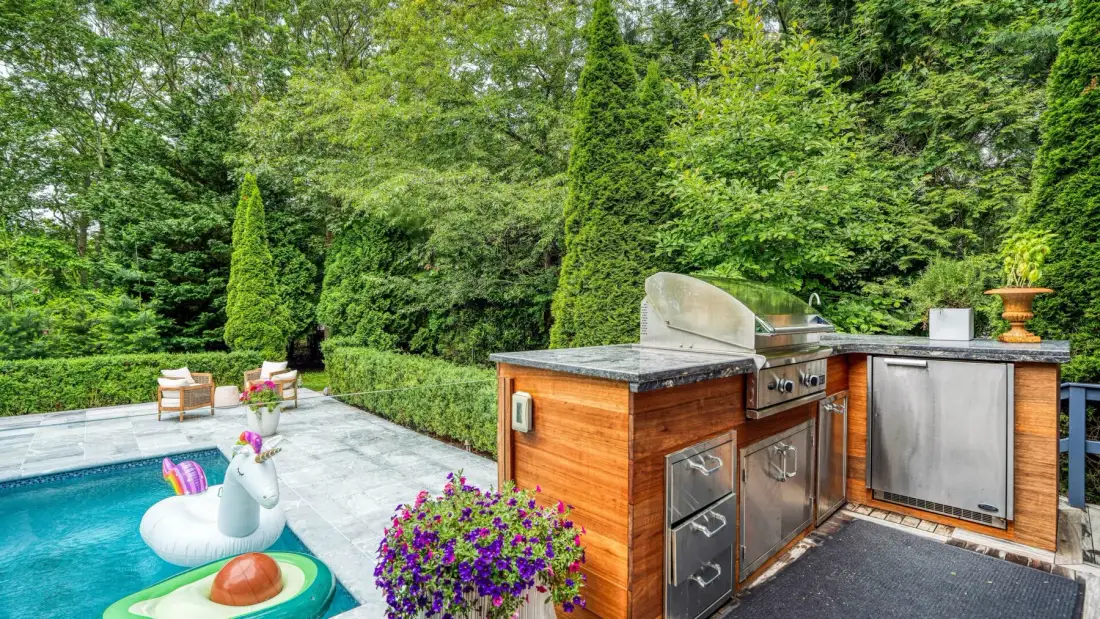 A garden patio features a swimming pool and an outdoor cooking area.