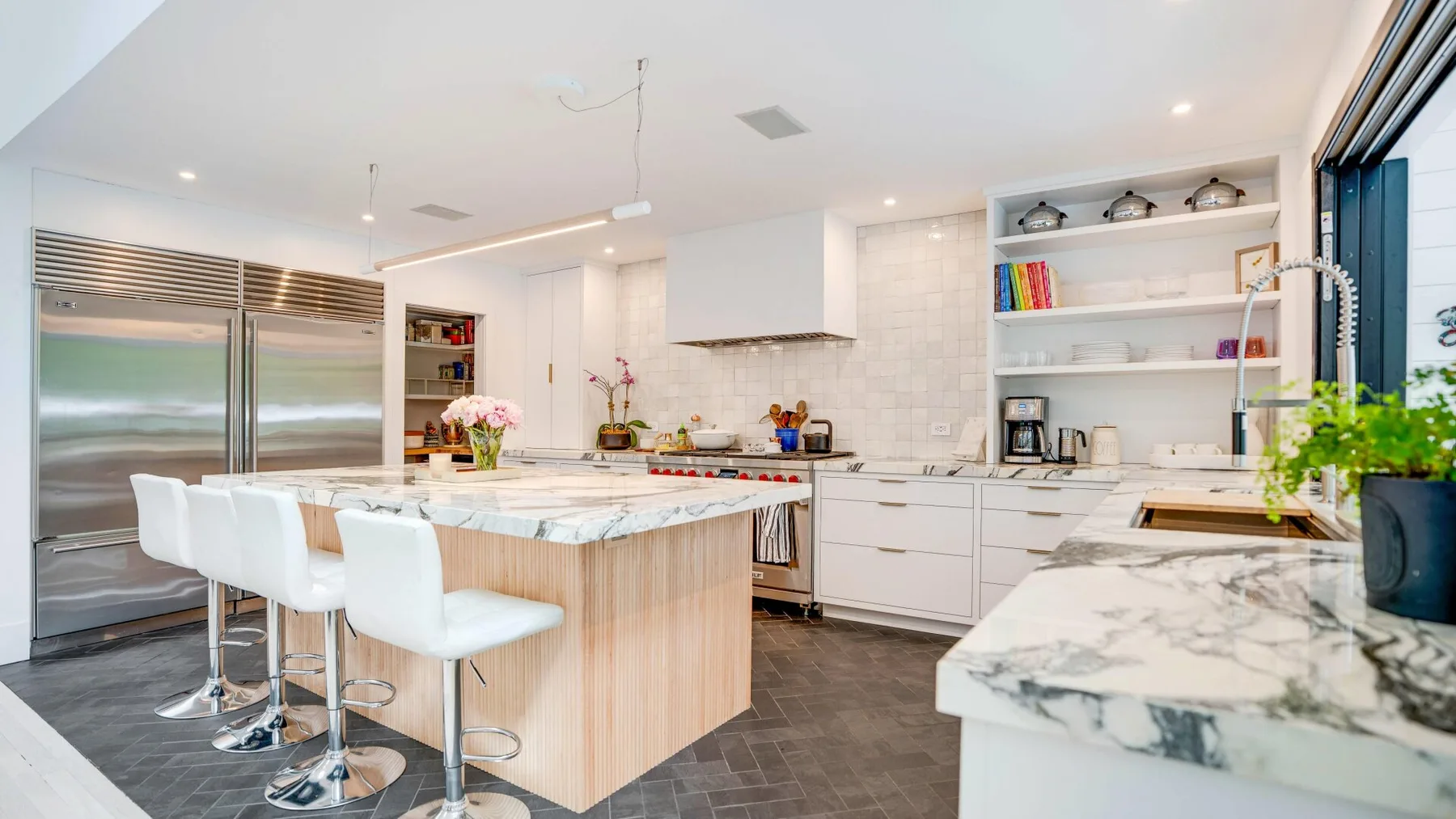 A modern kitchen with a central island, bar seating, and stainless steel appliances.