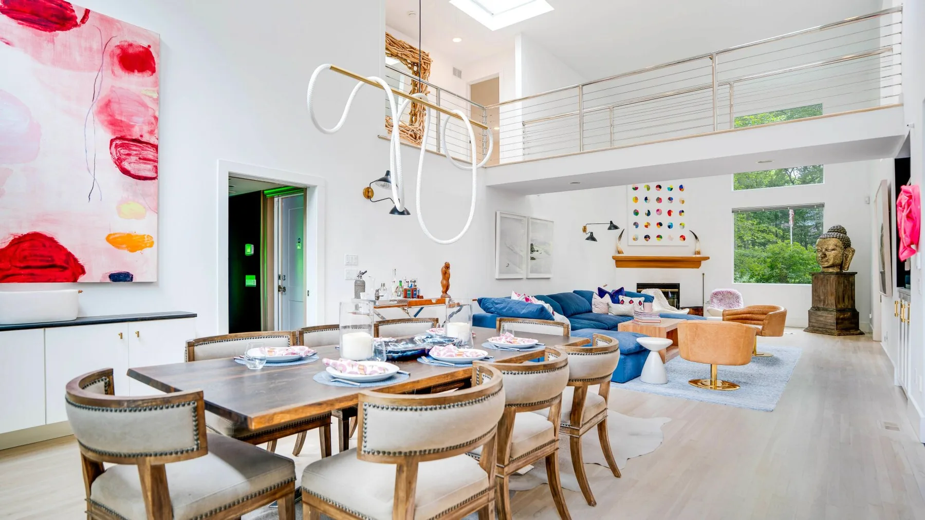 A bright open-plan dining and living area features a long table and blue seating.