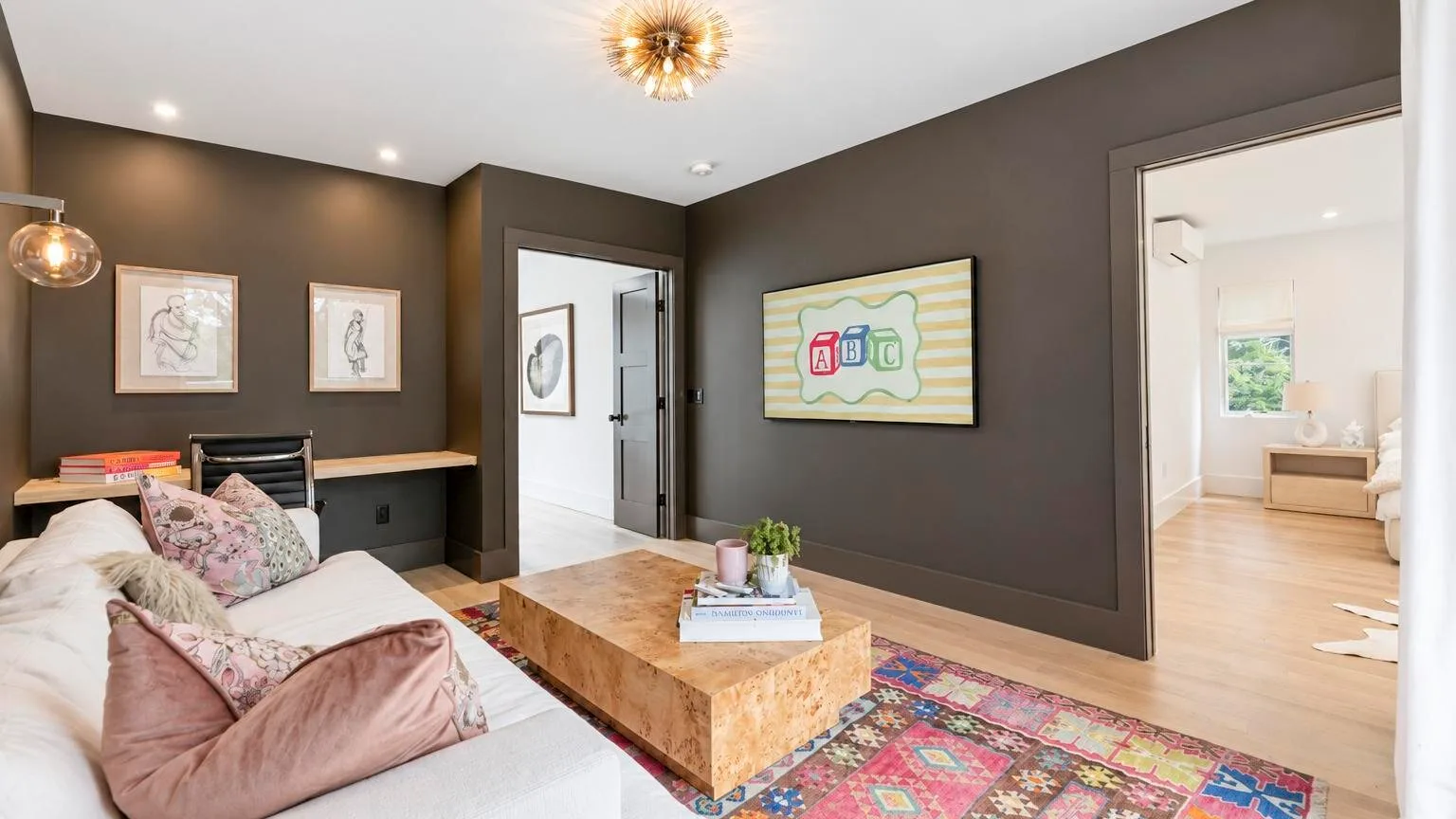 A dark-walled sitting room with a sofa, coffee table, and colorful rug.