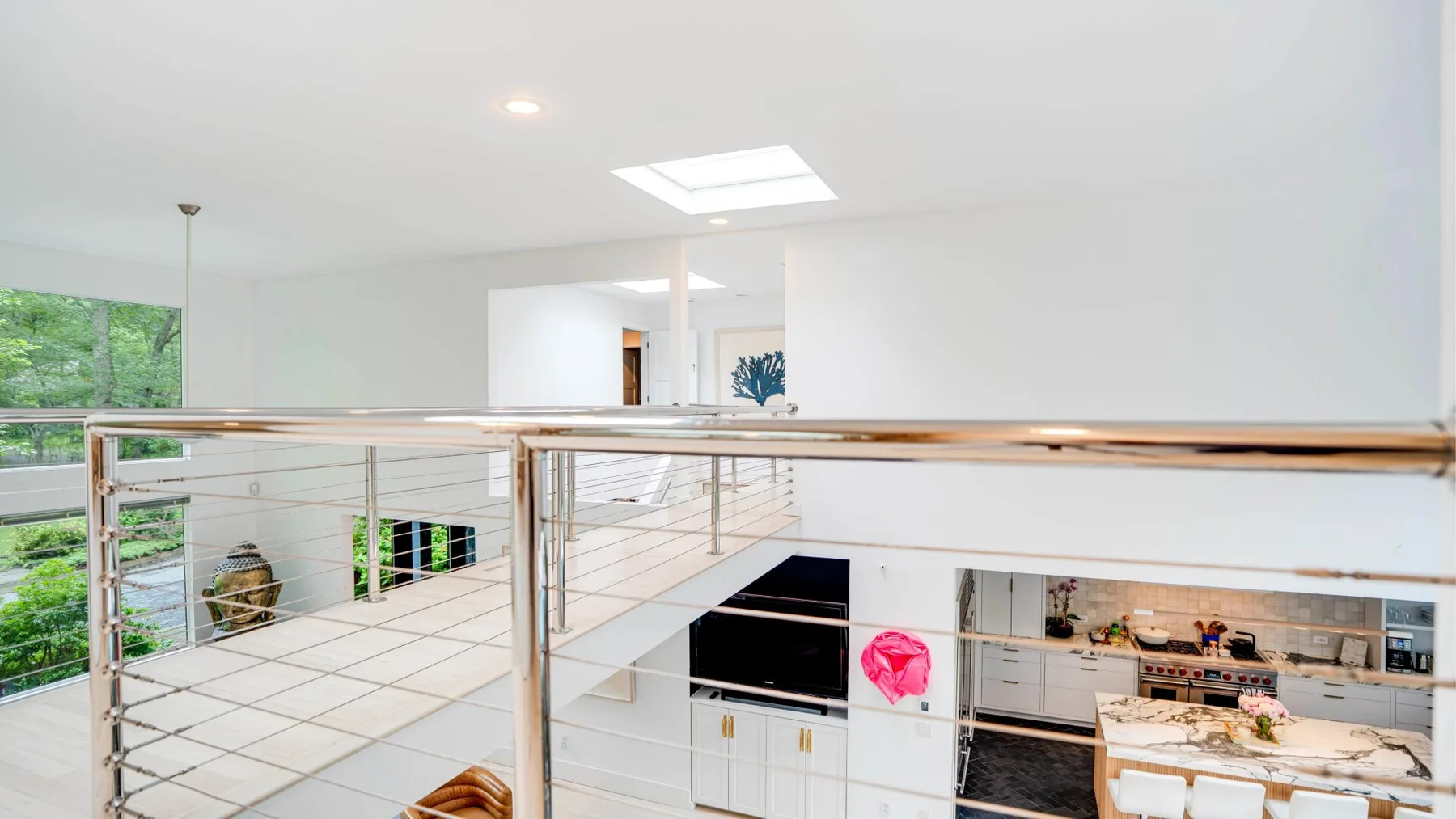 A bright open-plan kitchen and dining area sits beside a glass-railed upper landing.
