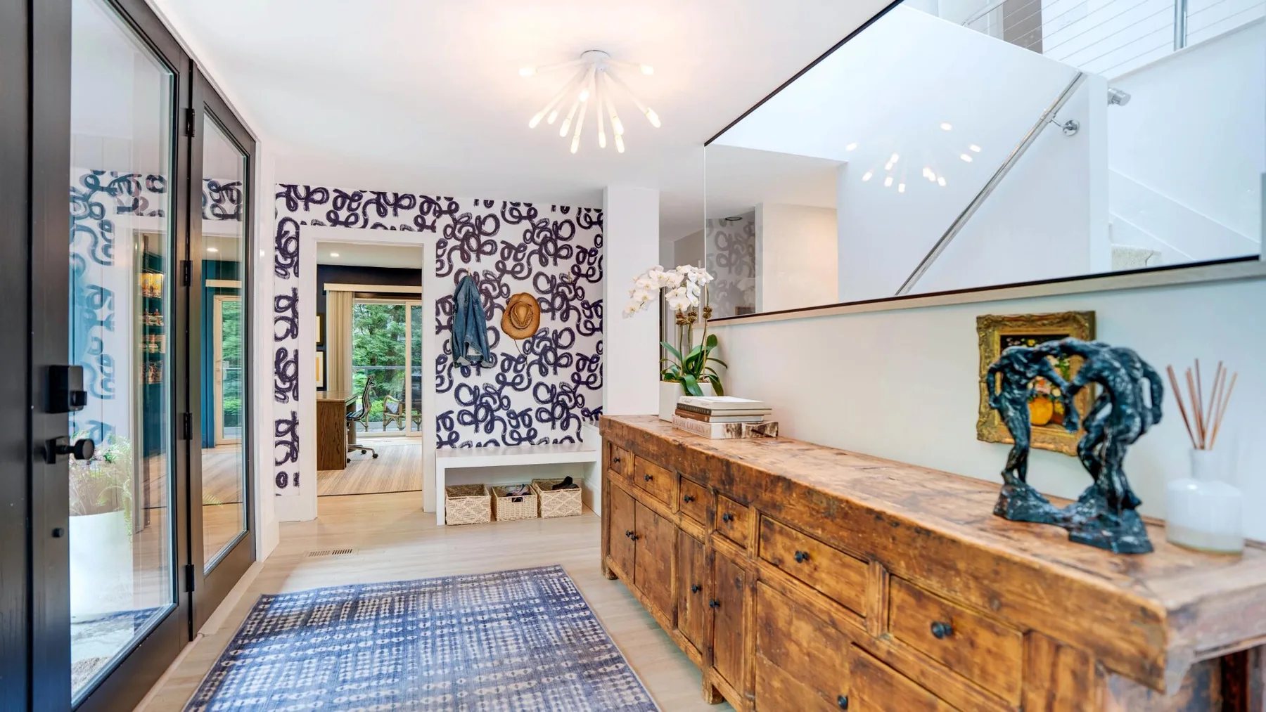 A bright entry hall features patterned walls and a long wooden console.