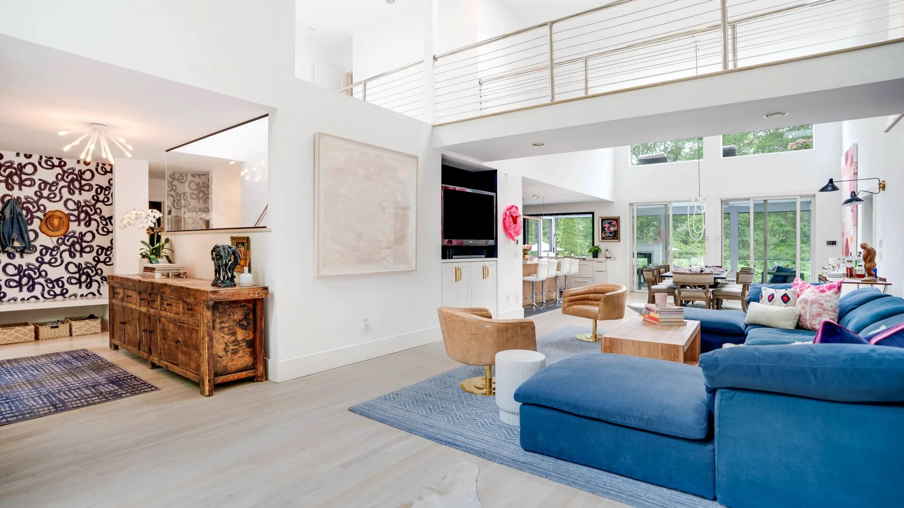 A bright open-plan living room with blue seating and a dining area.