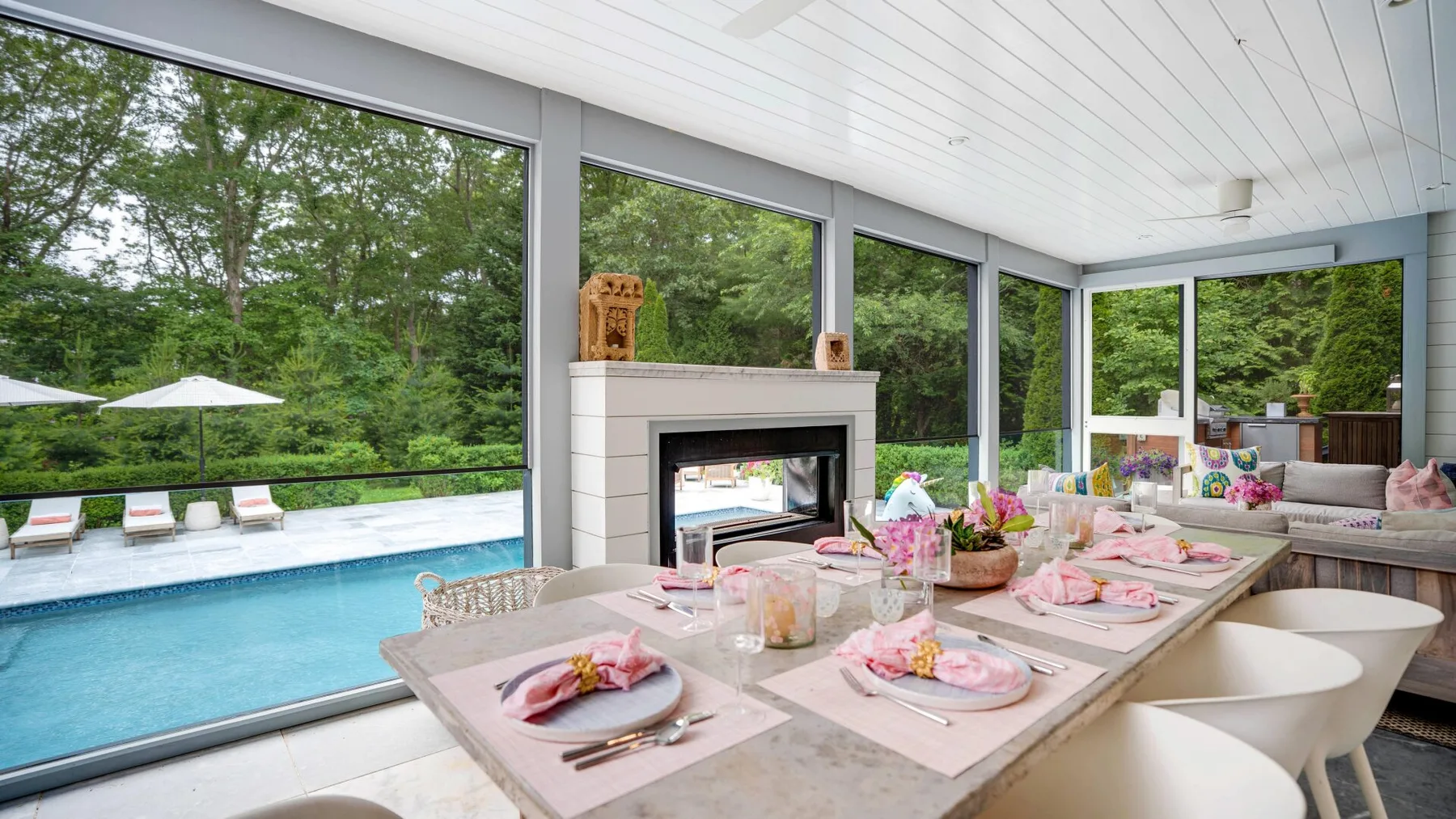 A bright dining area overlooks a swimming pool through wide windows.