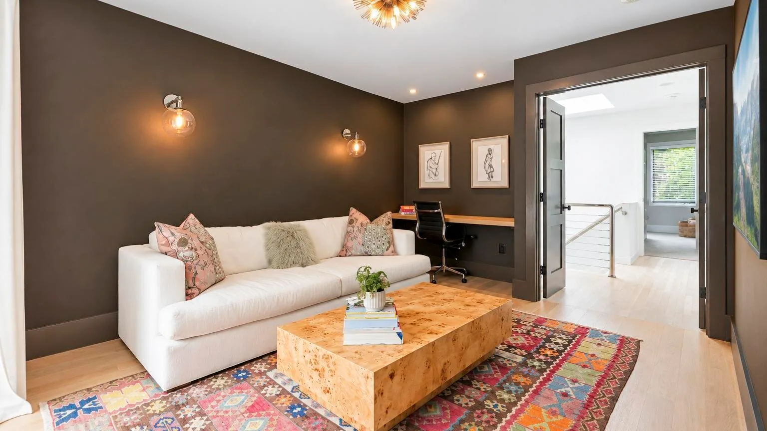 A dark-walled living room with a sofa, coffee table, and desk.