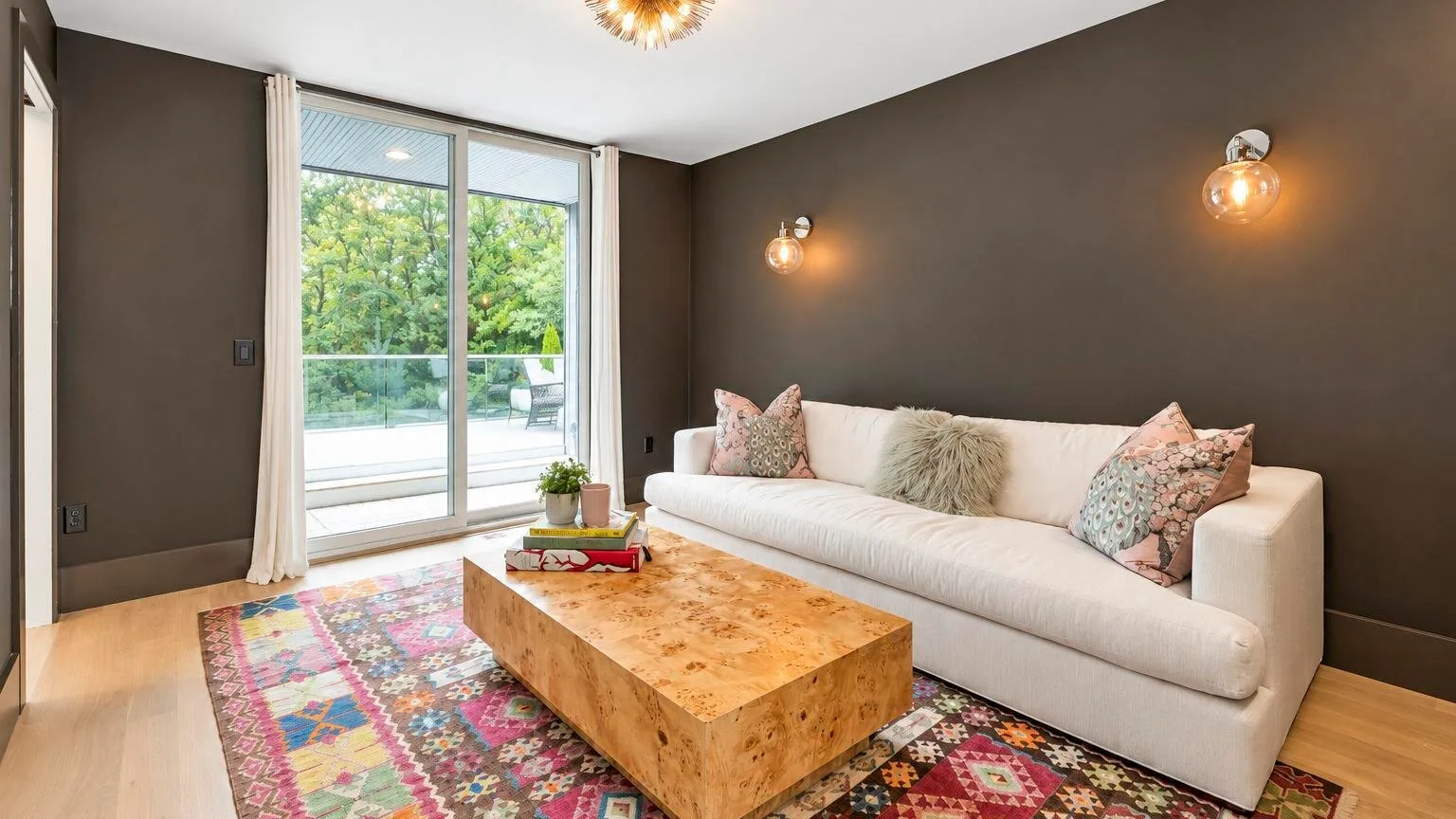A living room with a light-colored sofa, wooden coffee table, and large glass doors.