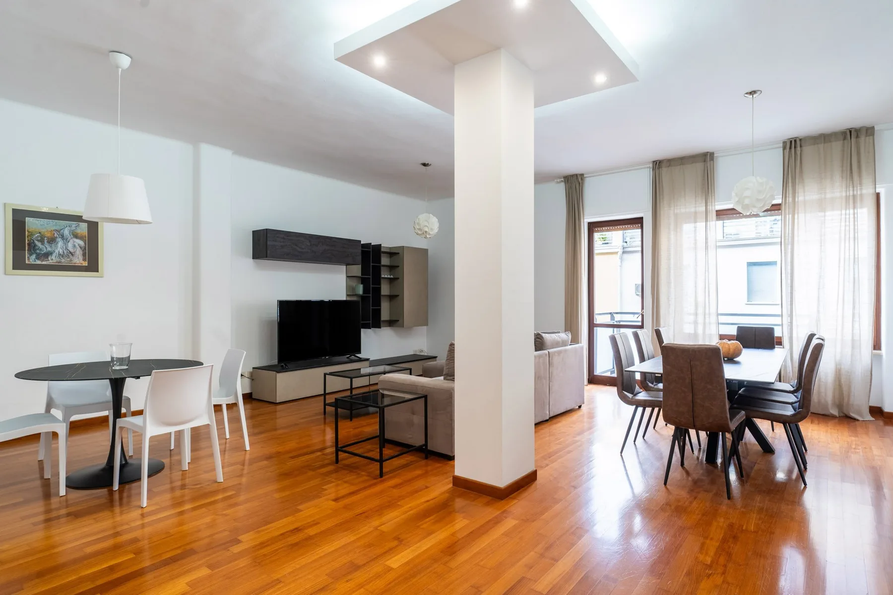 An open-plan living and dining area with a television and table seating.