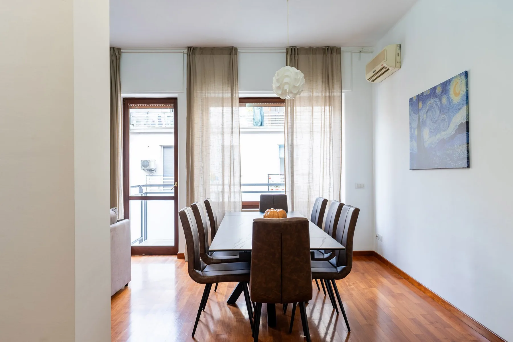 A dining area with a table and seating beside tall windows.
