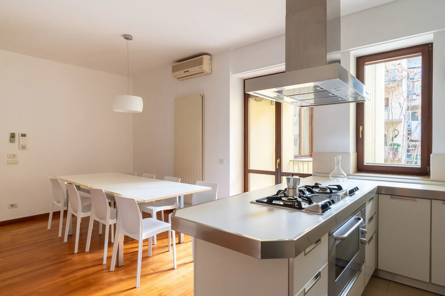 Una luminosa cocina-comedor con una isla con placa de cocción y una mesa larga.