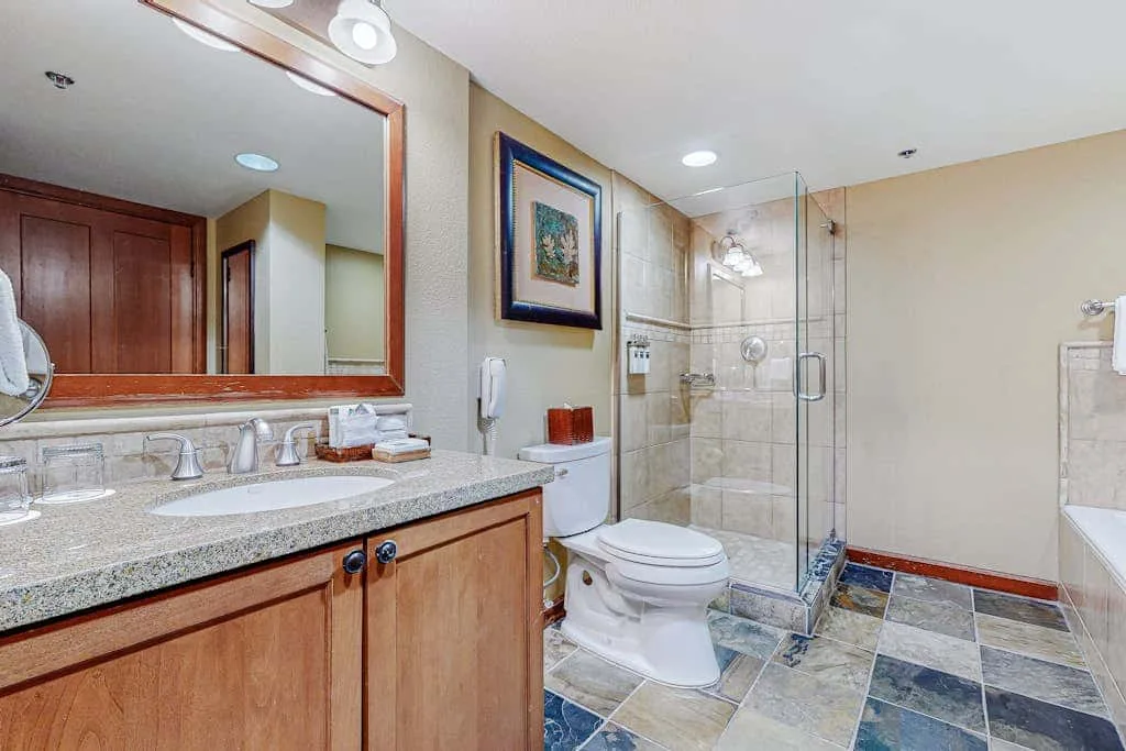 Un baño con lavabo, espejo, inodoro y ducha de vidrio.