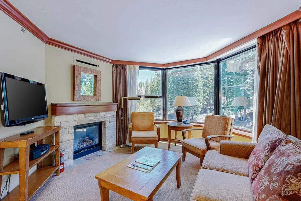 Una sala de estar con asientos, una chimenea y ventanas grandes.