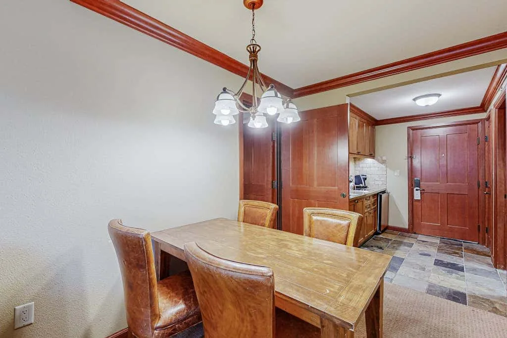 Un comedor con mesa y sillas de madera junto a la pequeña cocina.