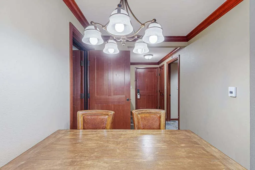 A dining area with a wooden table and chairs beneath a ceiling light.