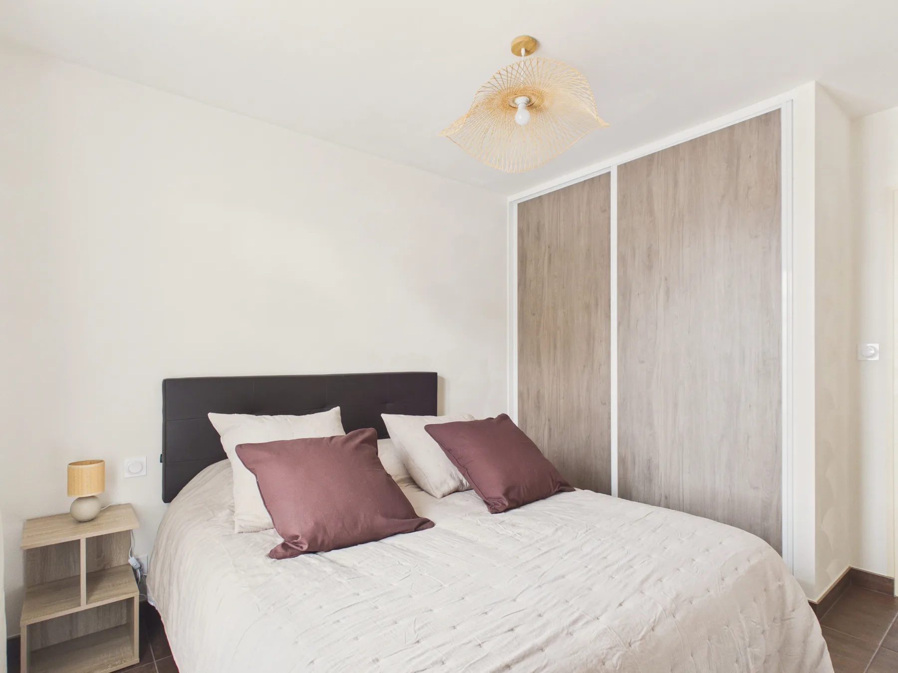 A bedroom with a double bed, white bedding, and a large wardrobe.