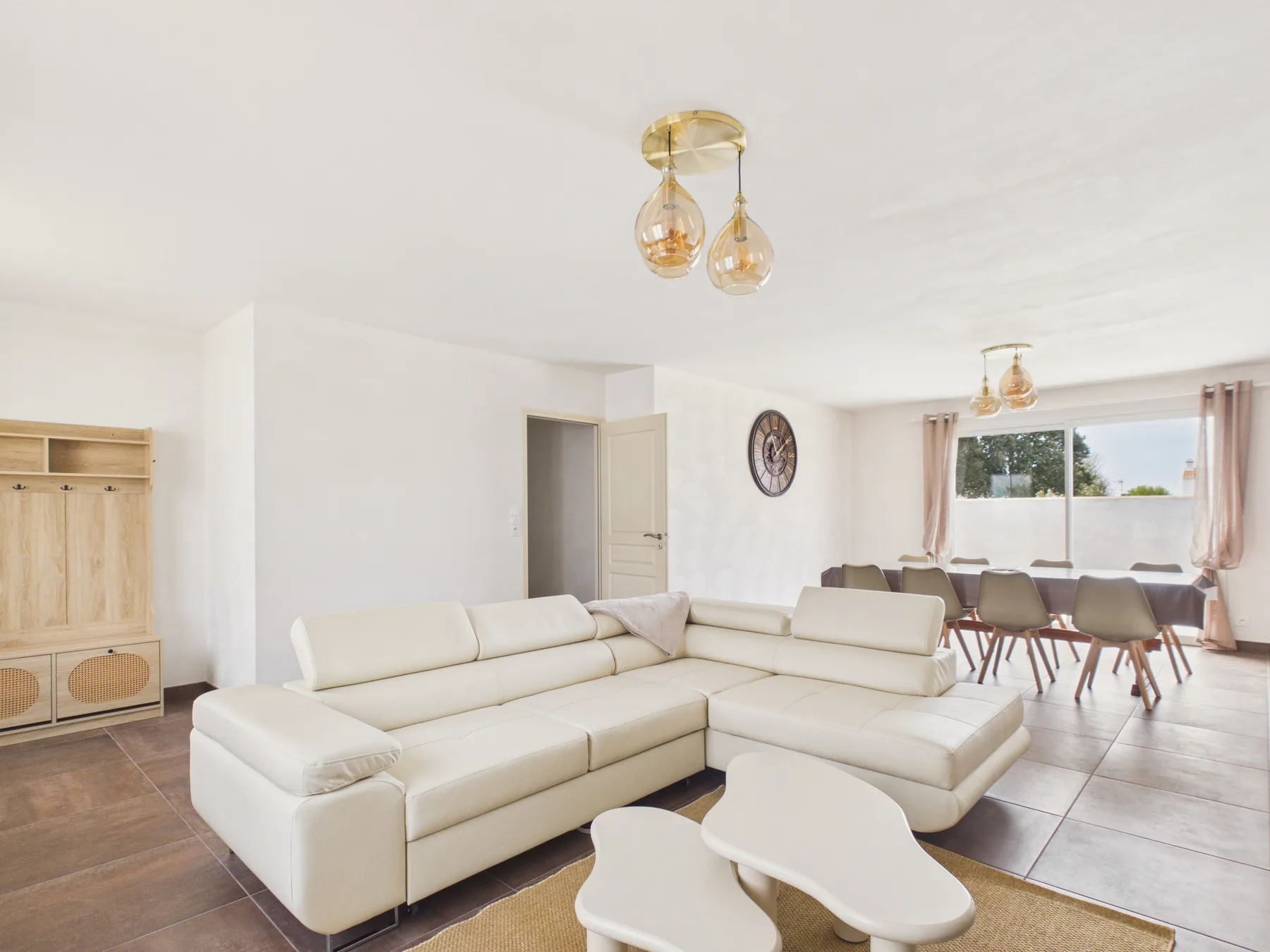 A bright living and dining area with a white sectional sofa and dining table.