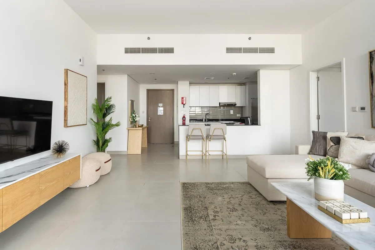 Una luminosa sala de estar se conecta con una cocina, con sofá y televisor.