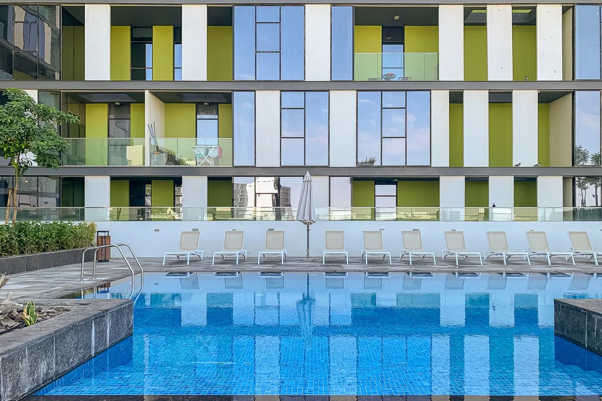 Una piscina con asientos de descanso está frente a un edificio moderno.