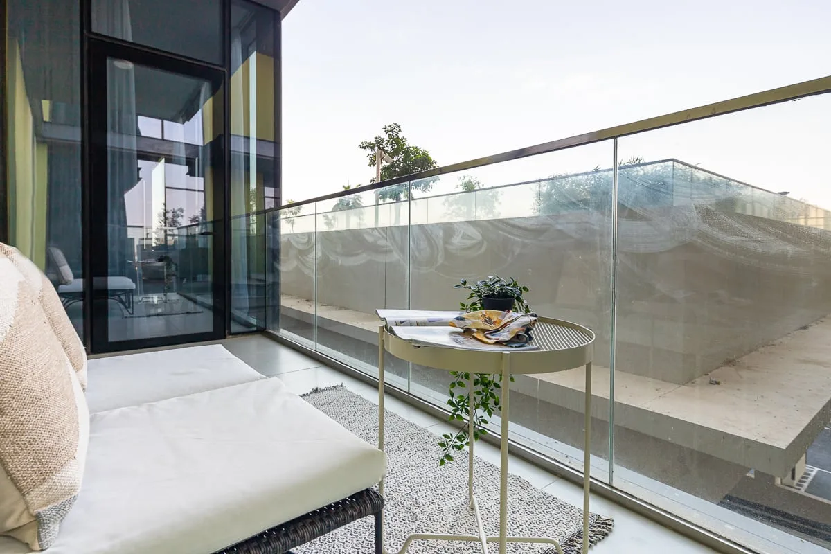 Un balcón moderno con una zona de asientos acolchados y una pequeña mesa redonda.
