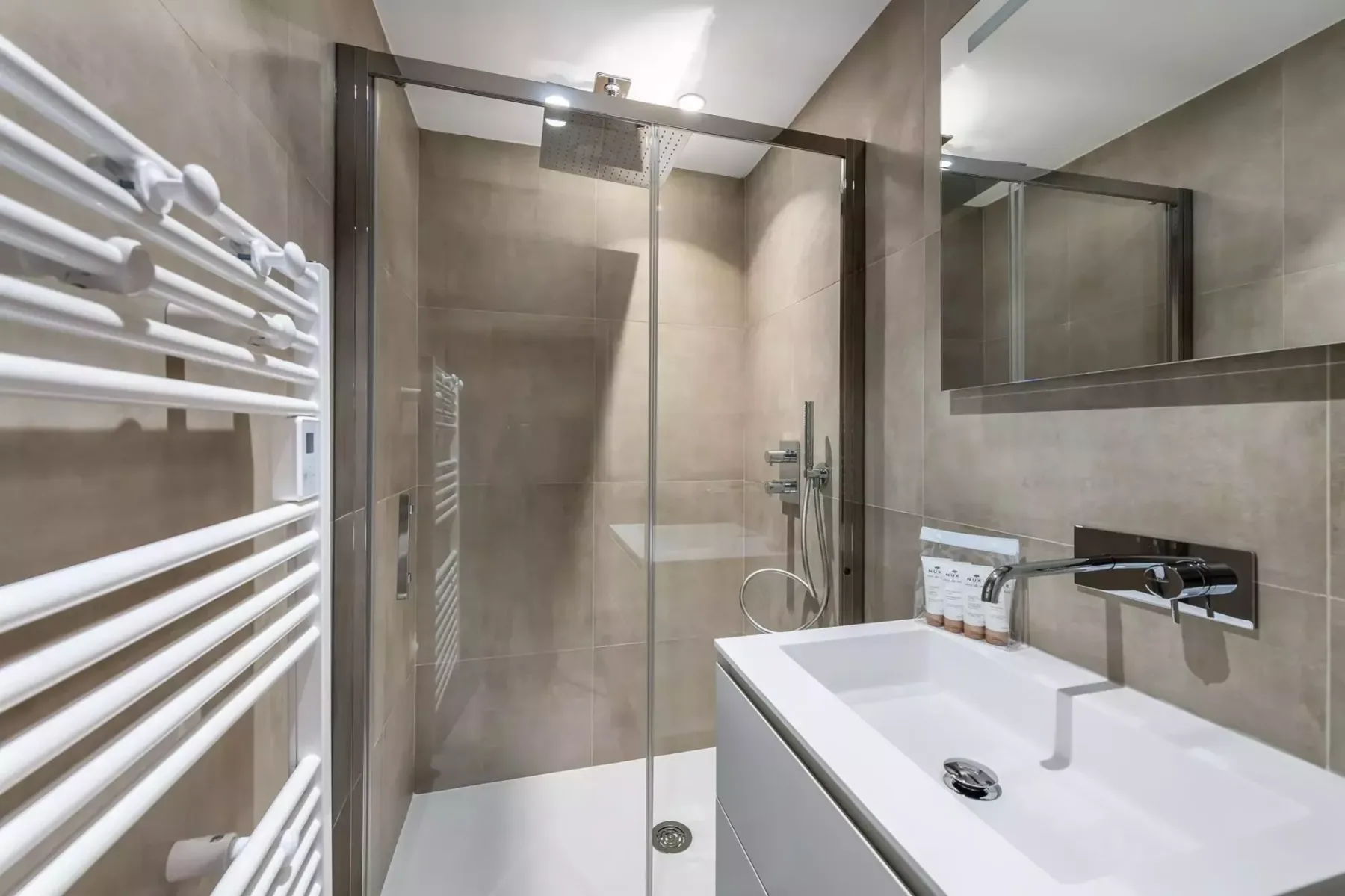 Un baño moderno con una ducha de vidrio y un lavabo blanco.