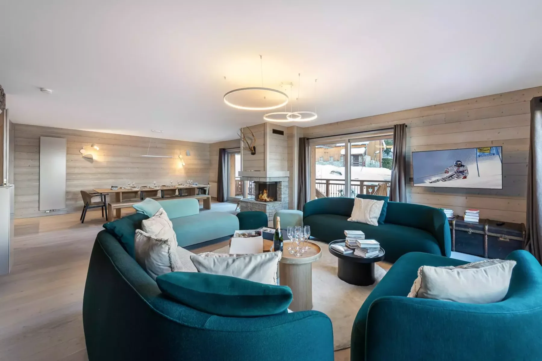 A living room with curved teal seating, a fireplace, and windows.