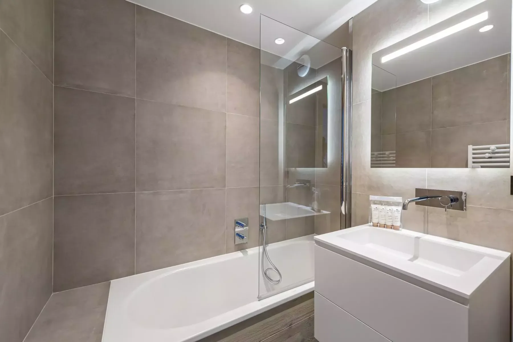 Un baño moderno con bañera, mampara de vidrio y lavabo.