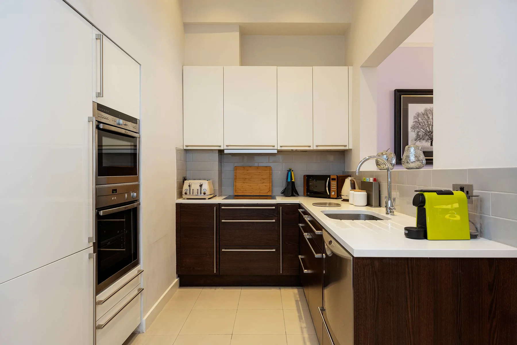 Una cocina moderna con gabinetes inferiores oscuros y una isla blanca.