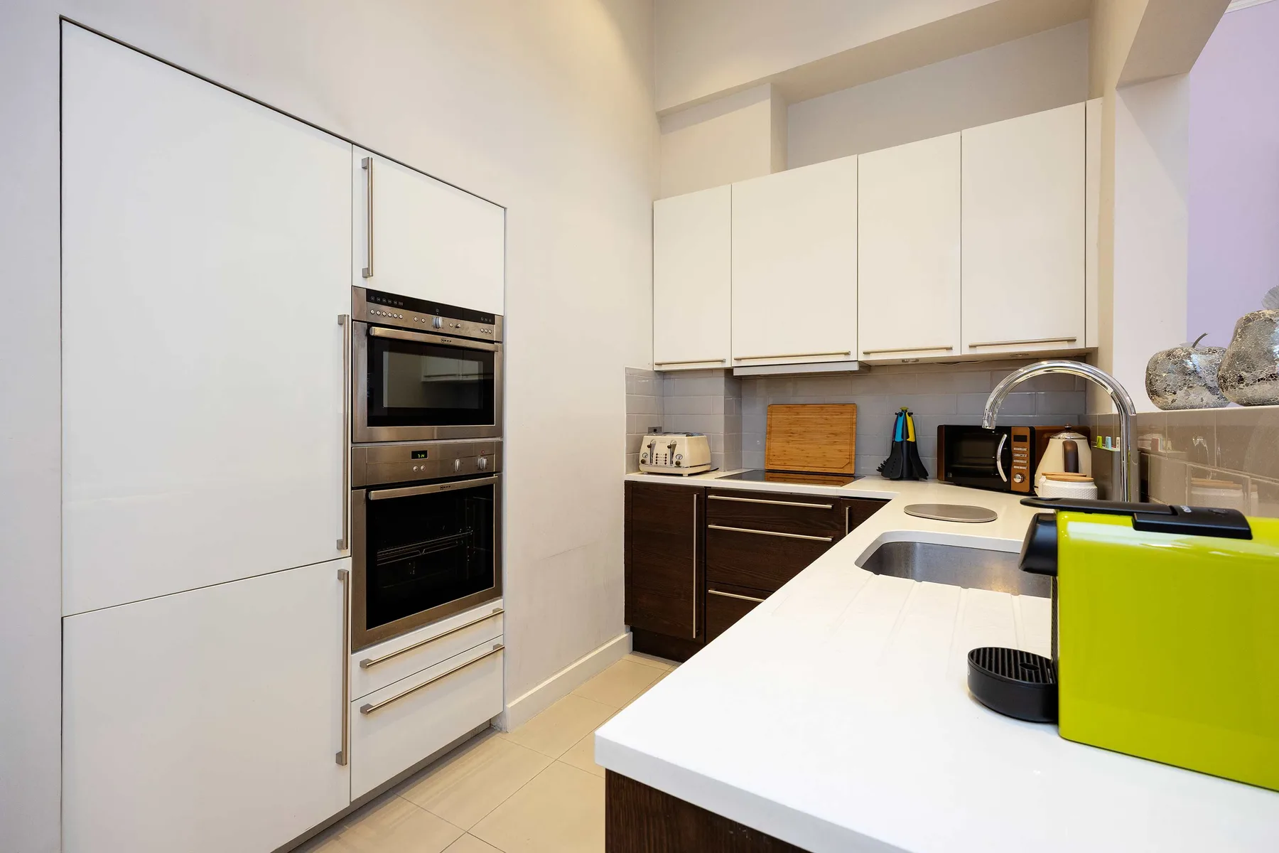 Una cocina moderna con armarios blancos, muebles inferiores oscuros y una encimera.