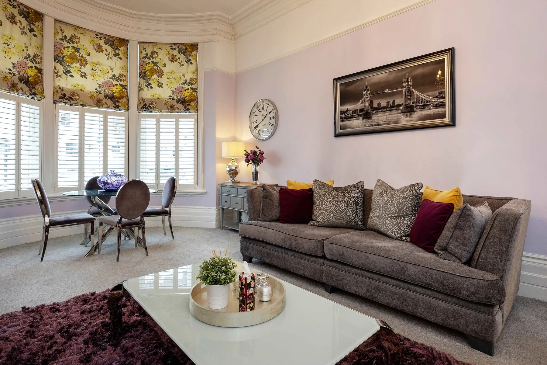 Una sala de estar con un sofá gris y una mesa de centro de vidrio.