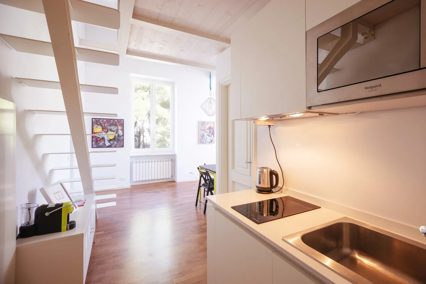 A bright kitchen with a cooktop and sink opens onto a dining area.
