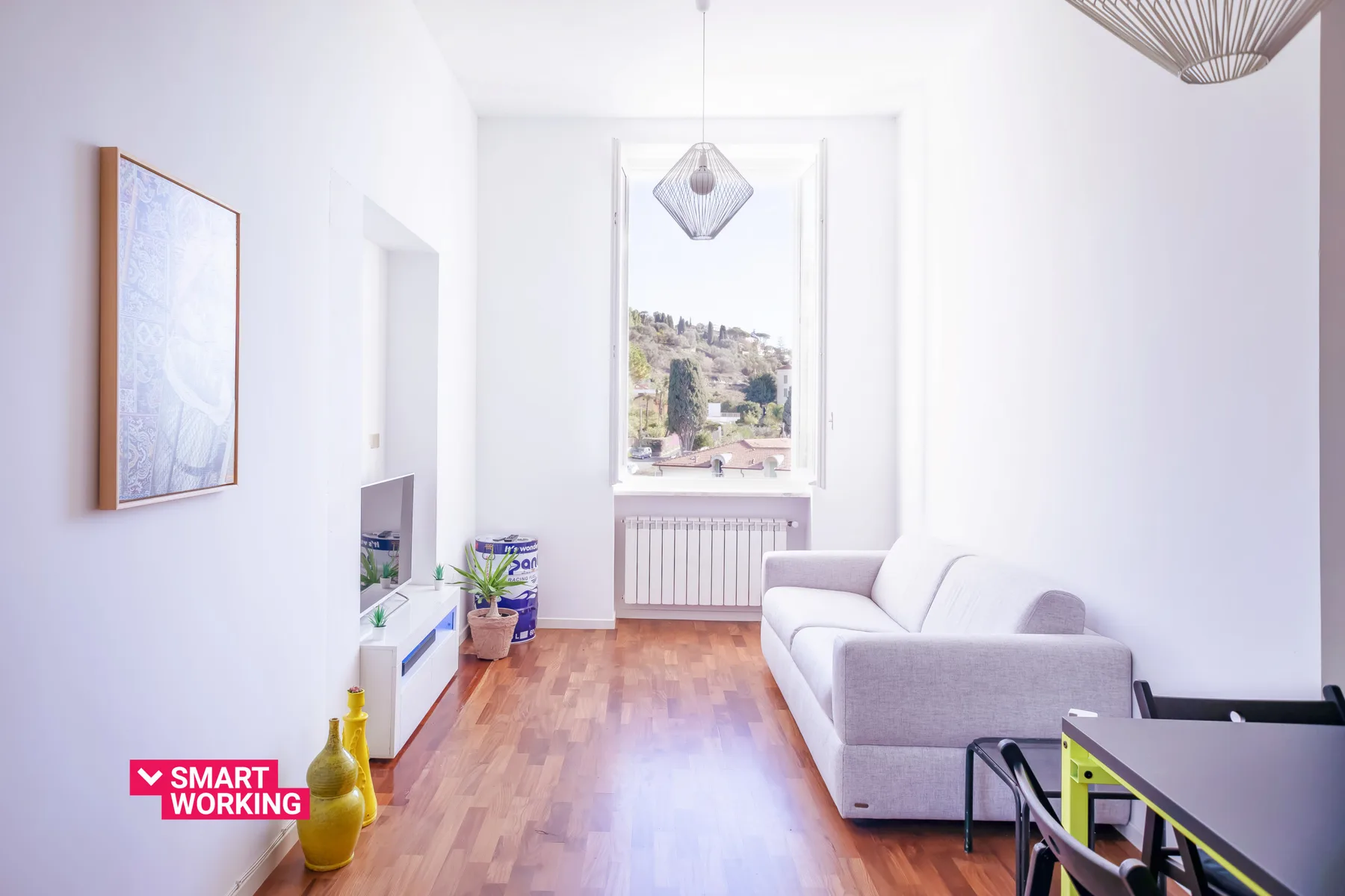 A bright living room with a light-colored sofa and a window overlooking a hillside.