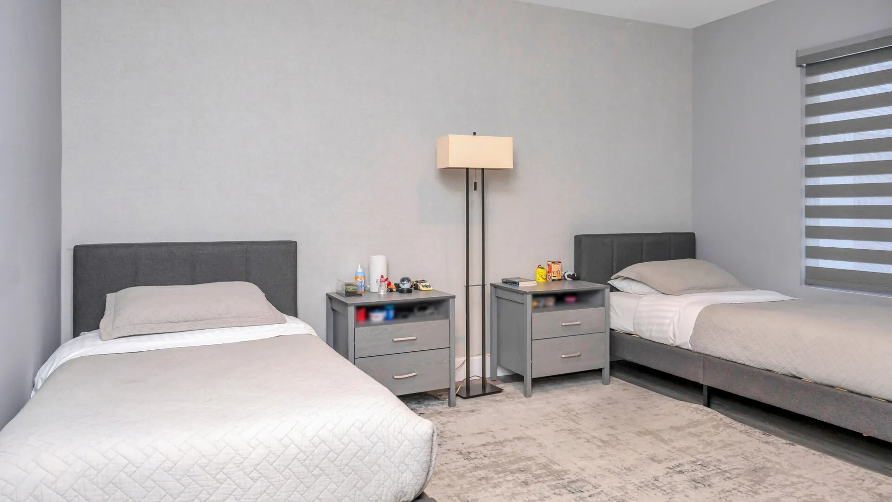 Un dormitorio con dos camas, mesitas de noche y una lámpara de pie.