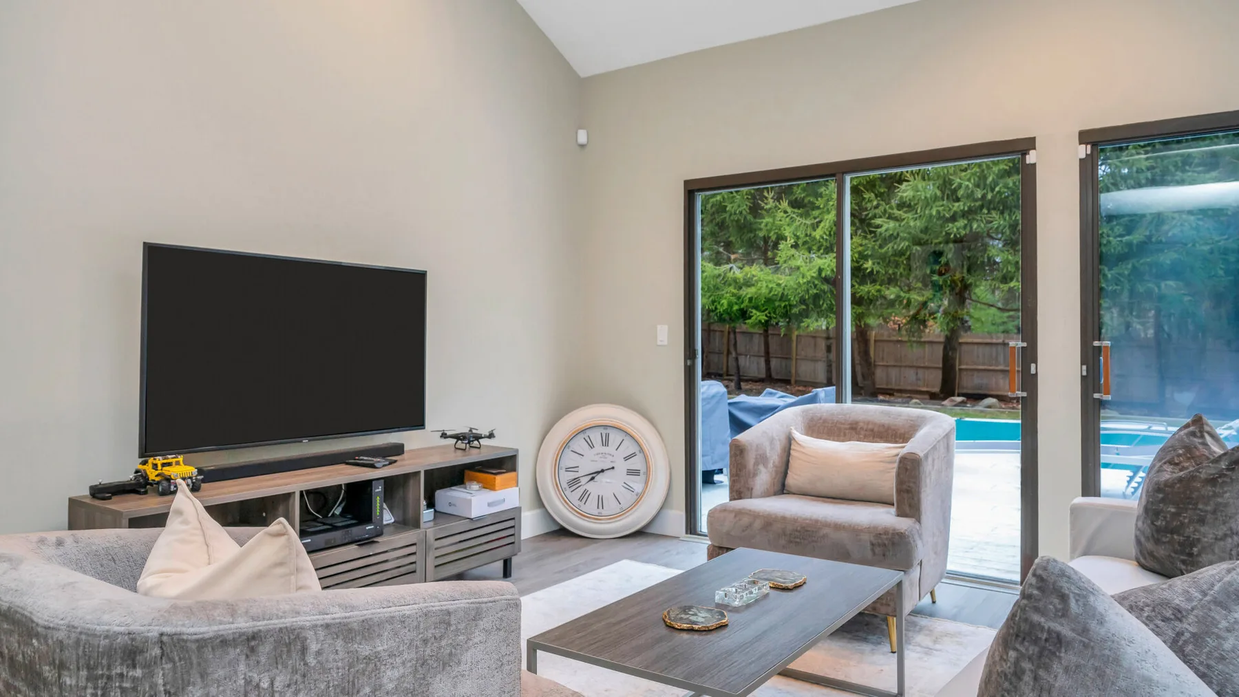 Una sala luminosa con asientos, un televisor y puertas de vidrio que dan a un patio.