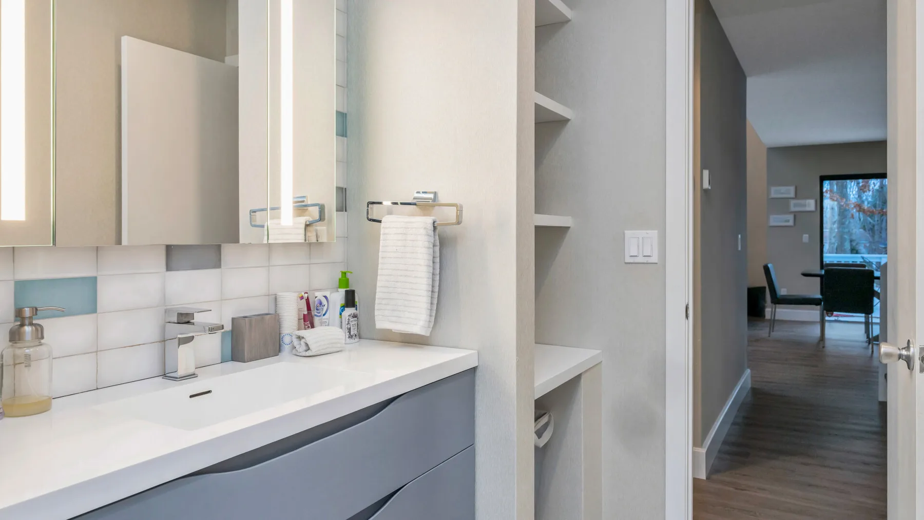 Un tocador de baño luminoso con encimera blanca y espejo de pared.