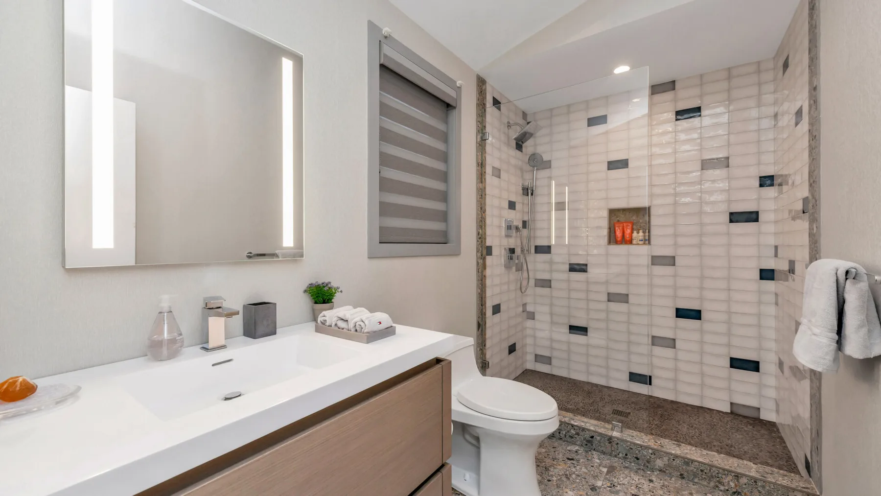 Un baño moderno con un tocador amplio y una zona de ducha alicatada.