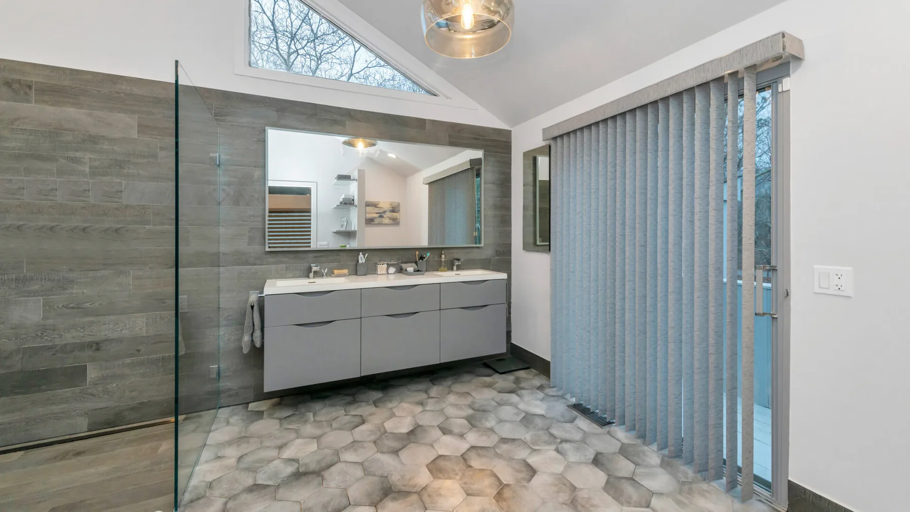 Un baño moderno con un amplio tocador y paredes revestidas de azulejos.