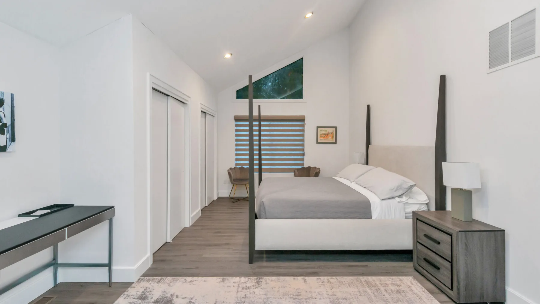 Un dormitorio luminoso con una cama, una mesita de noche y un escritorio.