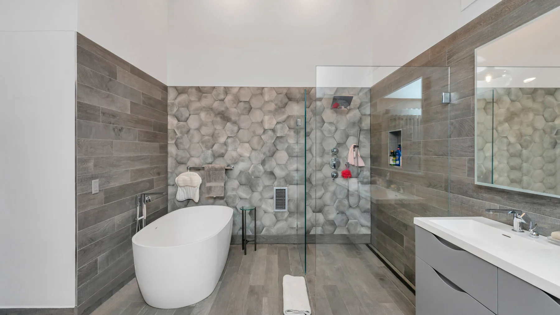 Un baño moderno con bañera exenta, ducha de vidrio y un tocador largo.
