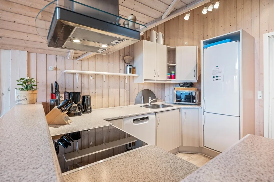 A compact kitchen with light wood cabinets and a countertop cooktop.