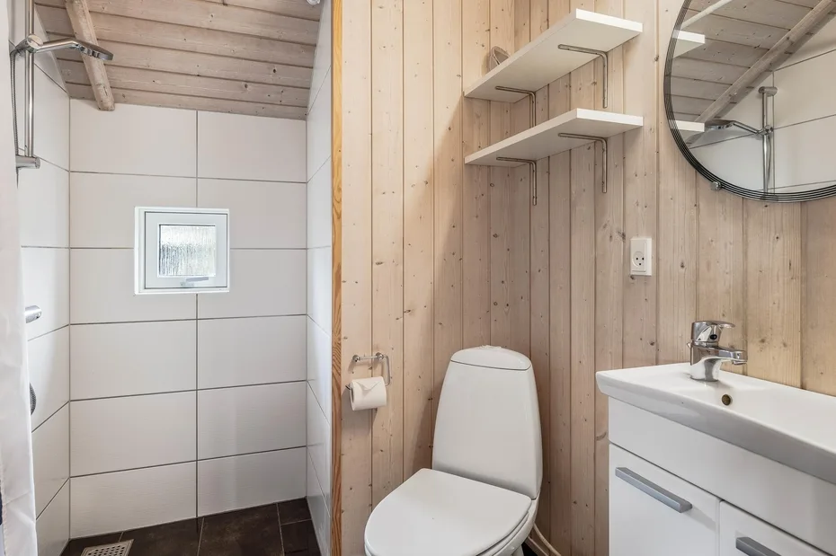 A bathroom with a toilet, sink, and shower area.