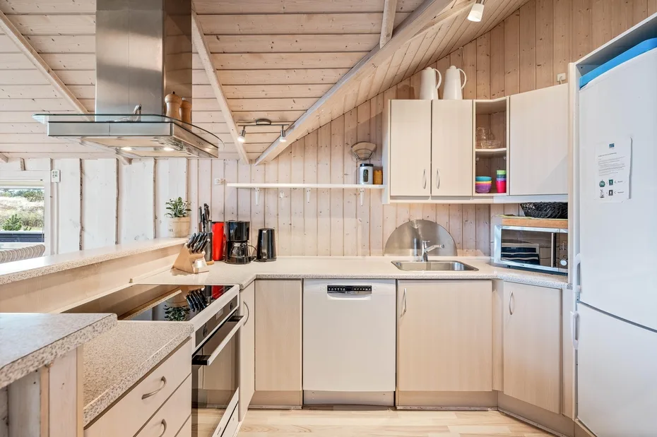 A bright kitchen with light wood cabinets, a countertop, and stainless steel appliances.