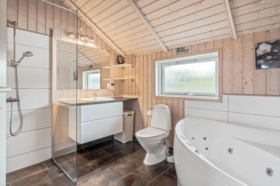 A wood-paneled bathroom with a shower, sink, toilet, and bathtub.