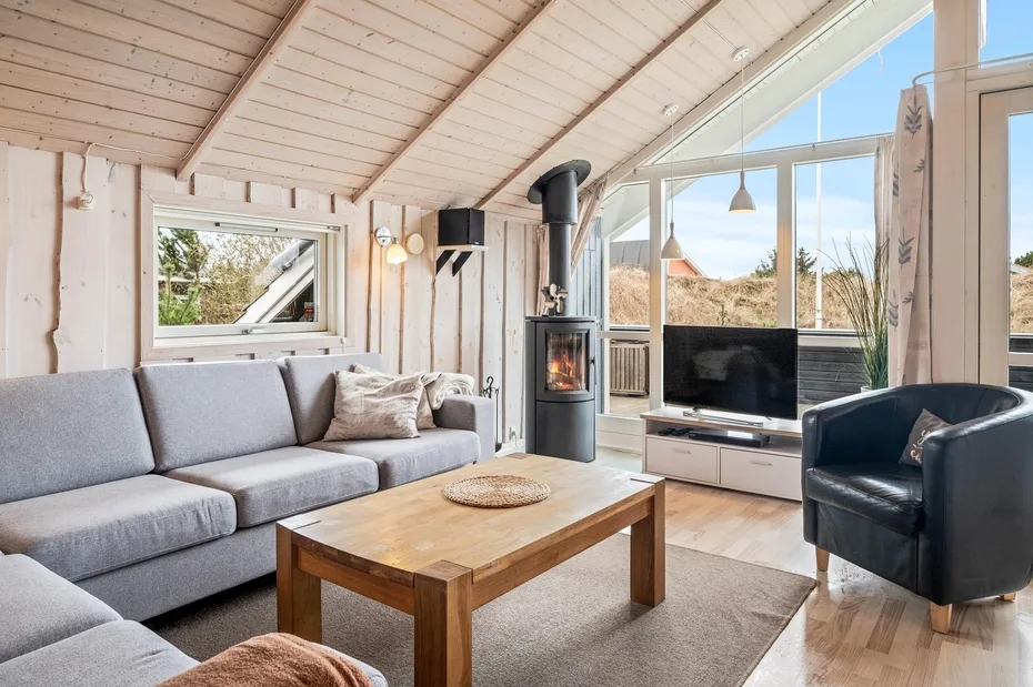 A bright living room with a gray sofa, wood coffee table, and large windows.
