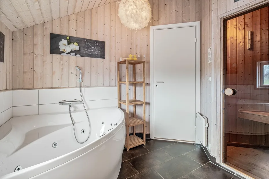 A bathroom with a large bathtub, shower fixture, and wooden walls.