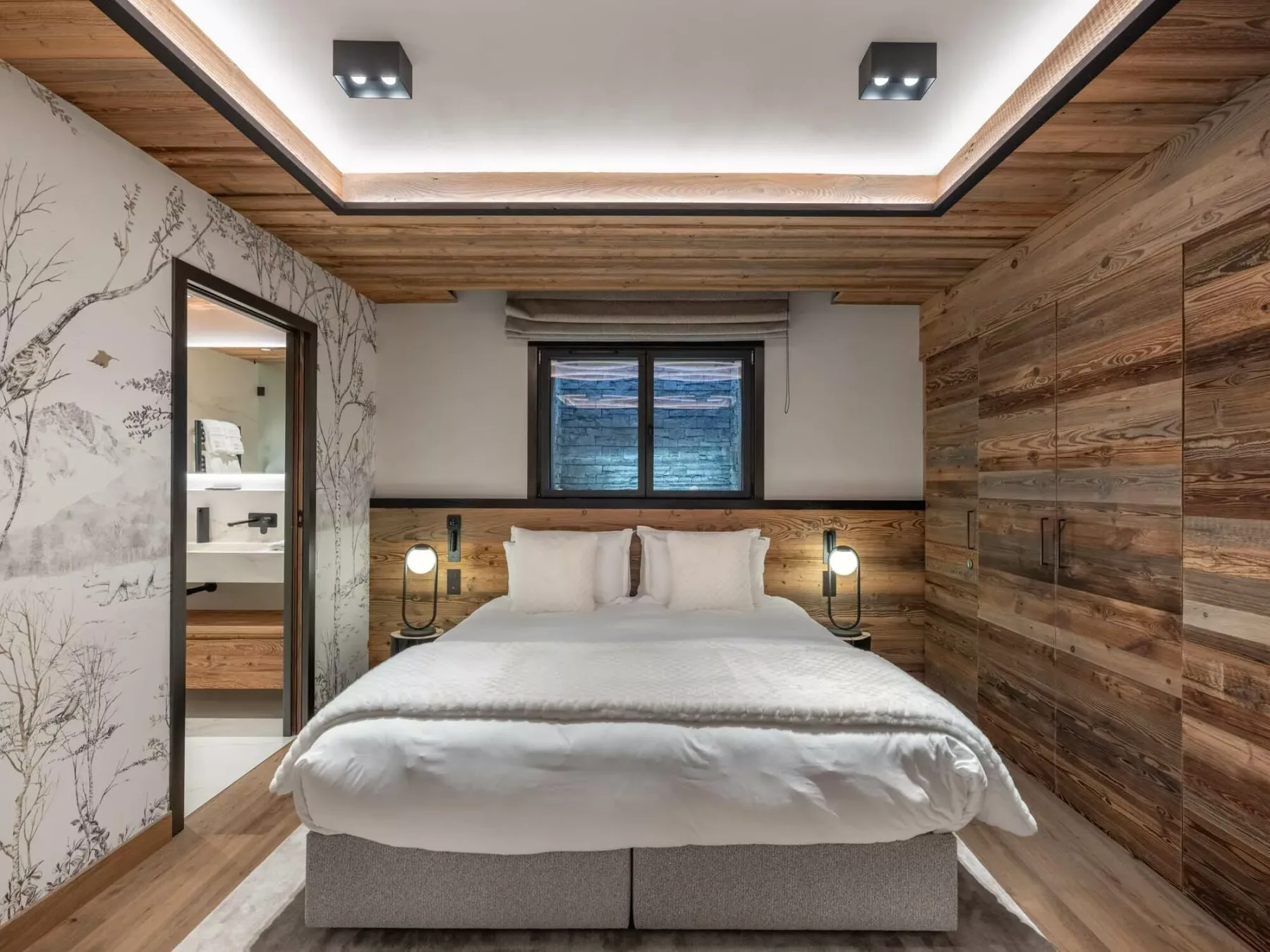 Un dormitorio con una cama tendida, lámparas de noche y una ventana.