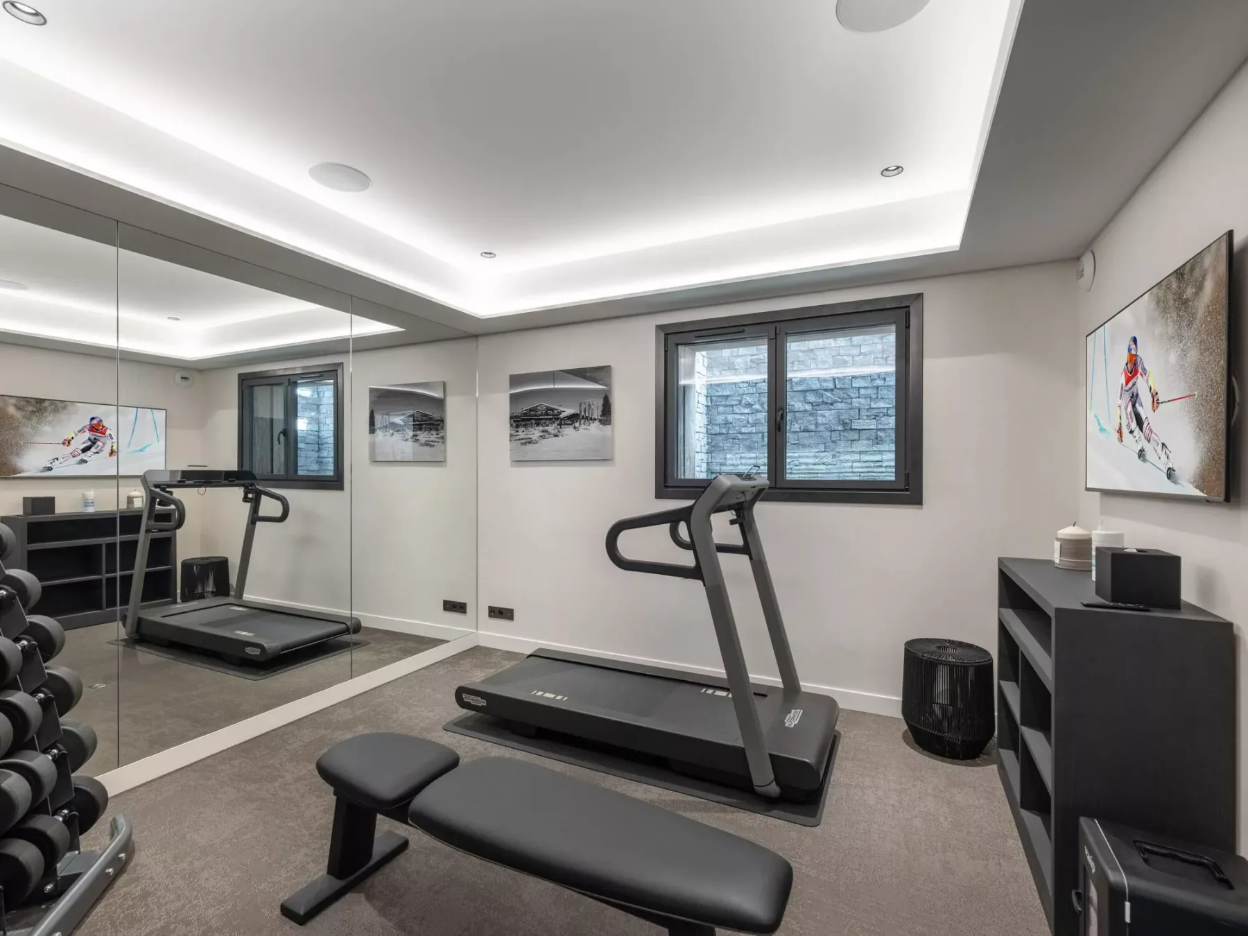 Un gimnasio en casa con una cinta de correr, pesas y una pared con espejo.
